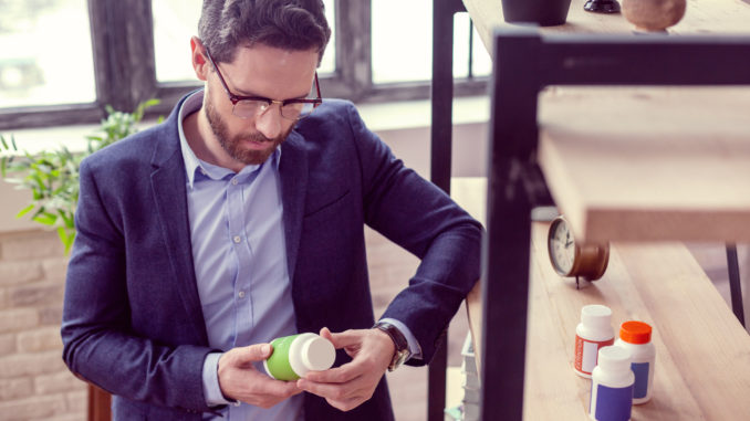 man reading an inscription on the bottle