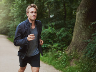 Three Quarter Shot of a Healthy Young Man in Jacket Shirt, Jogging at the Park Early in the Morning.