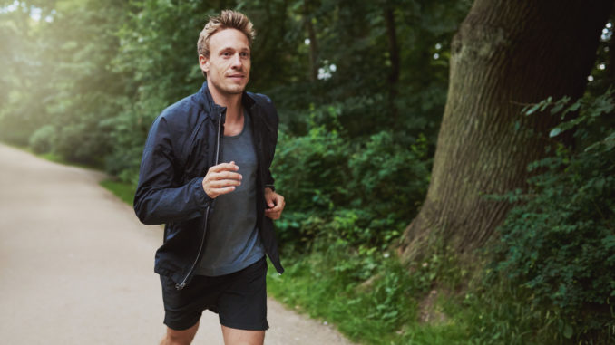 Three Quarter Shot of a Healthy Young Man in Jacket Shirt, Jogging at the Park Early in the Morning.