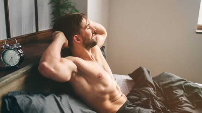 Sexy, happy bearded man in bed.