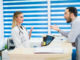 Man talking to female receptionist at hospital.