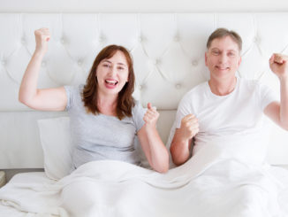 Happy smiling middle age couple in bed in t shirt