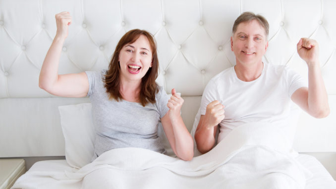 Happy smiling middle age couple in bed in t shirt