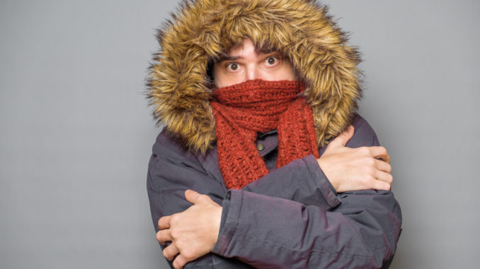 Studio portrait of man feeling cold and wearing warm clothes