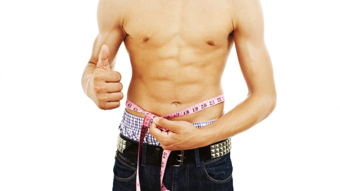 Man with a muscular body measuring his abs - lose weight series. Isolated on white background.