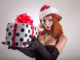 Pretty redhead pin-up girl in Santa Claus hat holding gift box, Christmas or holiday theme