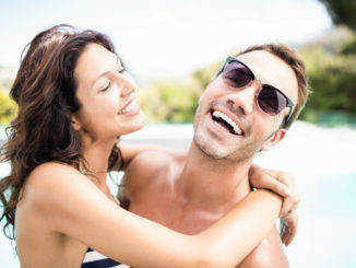 Young couple cuddling each other near pool at sunny day