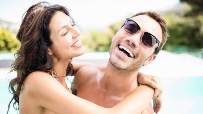 Young couple cuddling each other near pool at sunny day