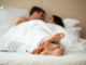 Couple`s feet in bed. Man with women under blanket. Rest in home comfort.
