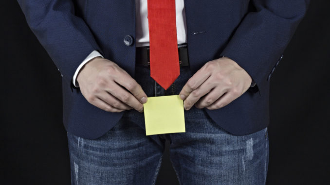 man holding sticker in his groin area, black background