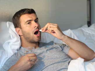 man taking medicine in bed.