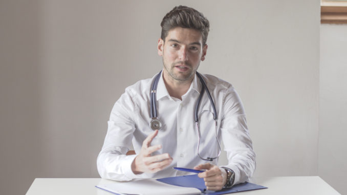 Frontal view of a young doctor talking to the camera.