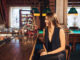 Beautiful young woman sitting at the bar talking with the bartender,the girl smiles in the bar