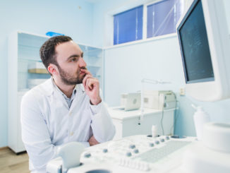 Portrait of a thinking doctor near sceen of medical equipment