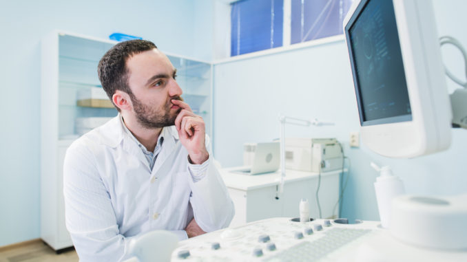 Portrait of a thinking doctor near sceen of medical equipment