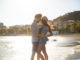 Portrait of happy couple cuddling at seaside in sunlight