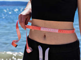 Attractive fit girl holding measuring tape around her waist