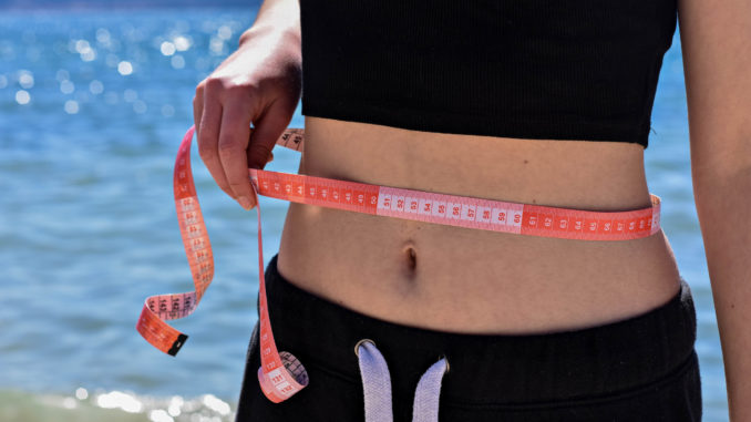 Attractive fit girl holding measuring tape around her waist