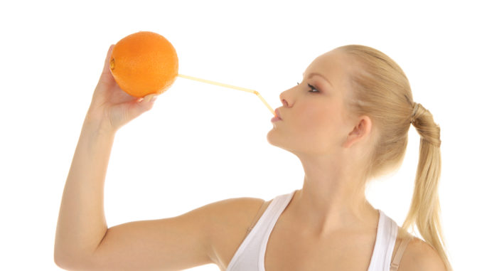 Woman drinking orange juice through a straw isolated on white