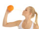 Woman drinking orange juice through a straw isolated on white