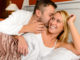 Happy couple in bed men giving kiss women cheek
