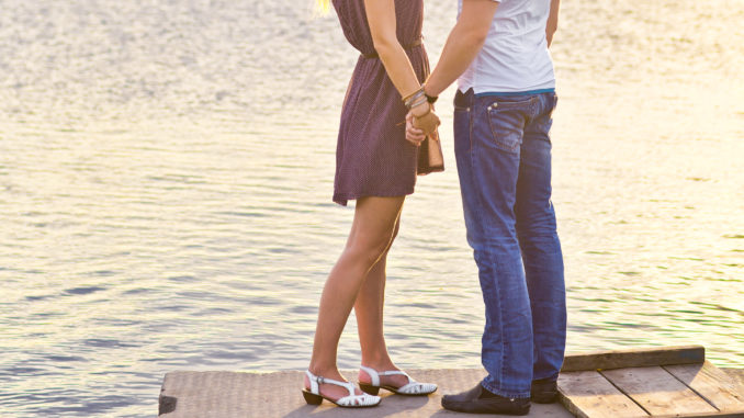 Happy couple hugging while standing on the bank of a river on summer