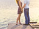 Happy couple hugging while standing on the bank of a river on summer