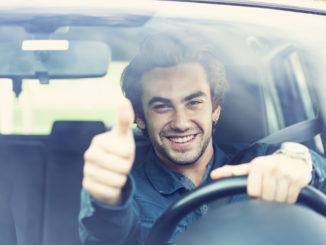 Young man thumbs up gesture in the car