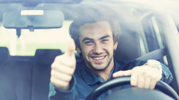 Young man thumbs up gesture in the car