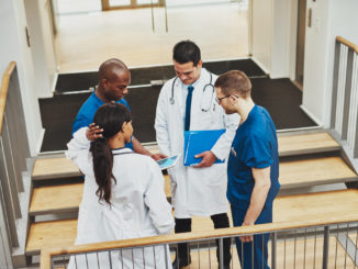 Confident team of doctors talking about a patient looking at tablet