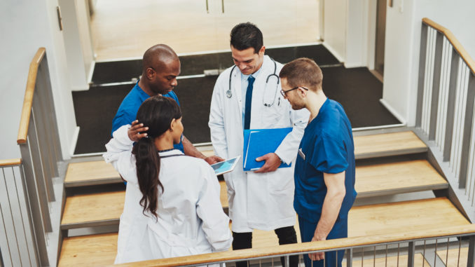 Confident team of doctors talking about a patient looking at tablet