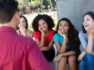 Group of multi ethnic girls flirting with one guy outdoors in summer