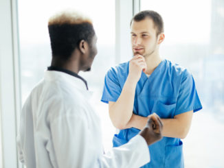 Two Doctors Talking As They Walk Through Modern Hospital