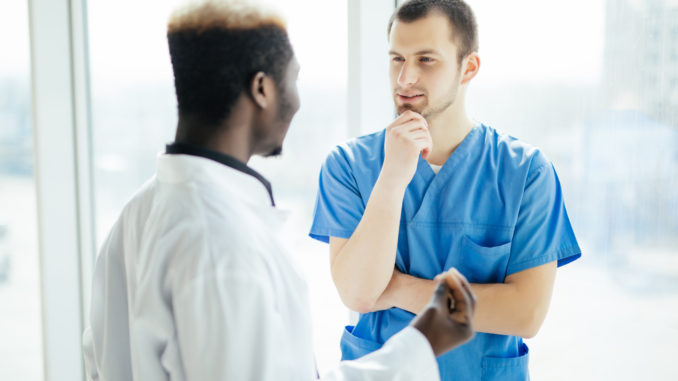 Two Doctors Talking As They Walk Through Modern Hospital