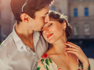 Young happy couple in love hugging and kissing outdoors.