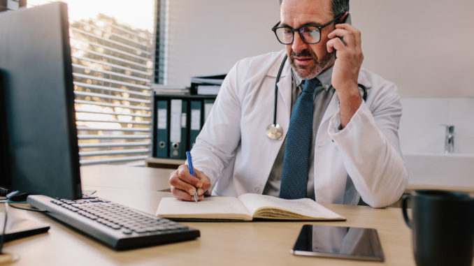 Medicine professional talking on phone and writing in his diary