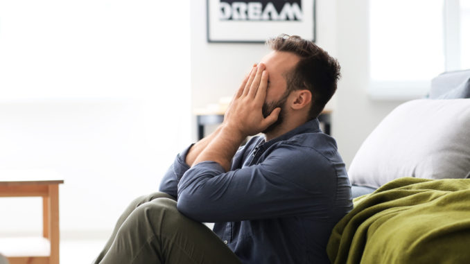 Stressed man sitting on floor at home