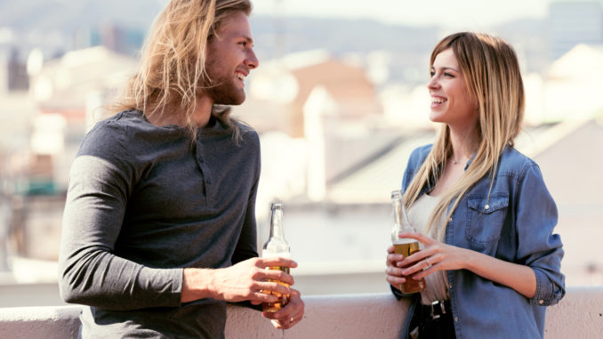 Shot of pretty young couple talking while drinking beer on the rooftop at home