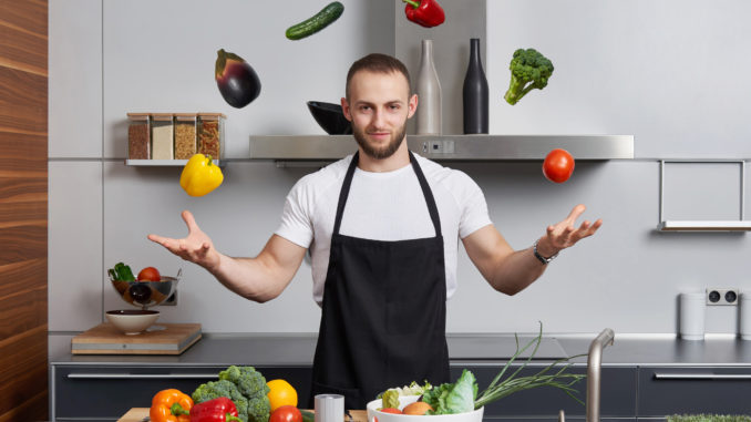 Young man in the kitchen juggling with vegetables