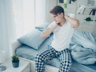 Portrait of upset sad man sit on bed wake up