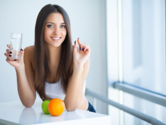 Beautiful Smiling Woman Taking Vitamin Pill and Dietary Supplement.