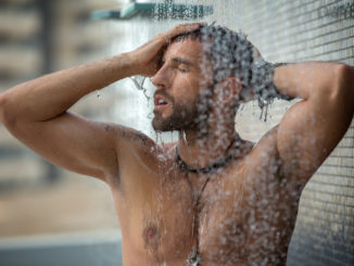 Naked man with a naked torso relaxes the shower.