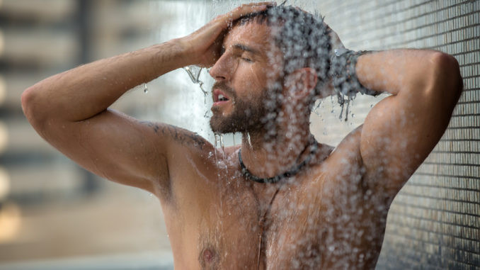 Naked man with a naked torso relaxes the shower.