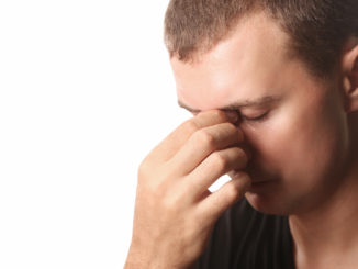 Young man with headache or sinus pain isolated on white background