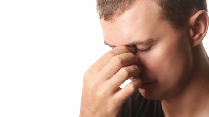 Young man with headache or sinus pain isolated on white background