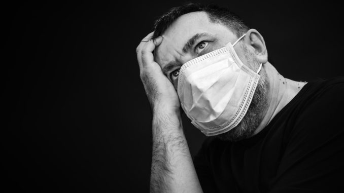 Black and white portrait of sick man in medical mask on dark background with copyspace