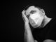Black and white portrait of sick man in medical mask on dark background with copyspace