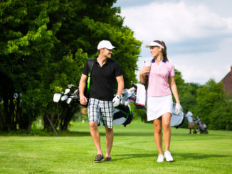 Young sportive couple playing golf on a golf course, they walking to the next hole