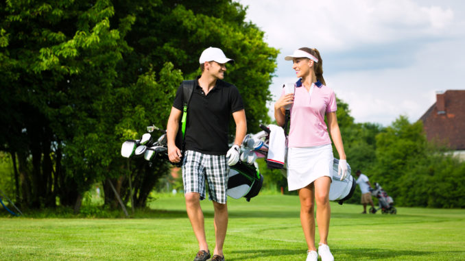 Young sportive couple playing golf on a golf course, they walking to the next hole