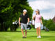 Young sportive couple playing golf on a golf course, they walking to the next hole